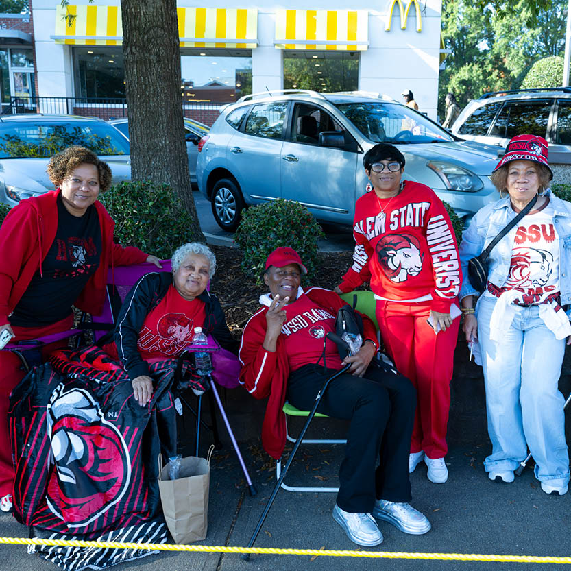 alumni seated on sidewalk viewing parade