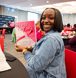 a smiling lady holding a book about breast cancer